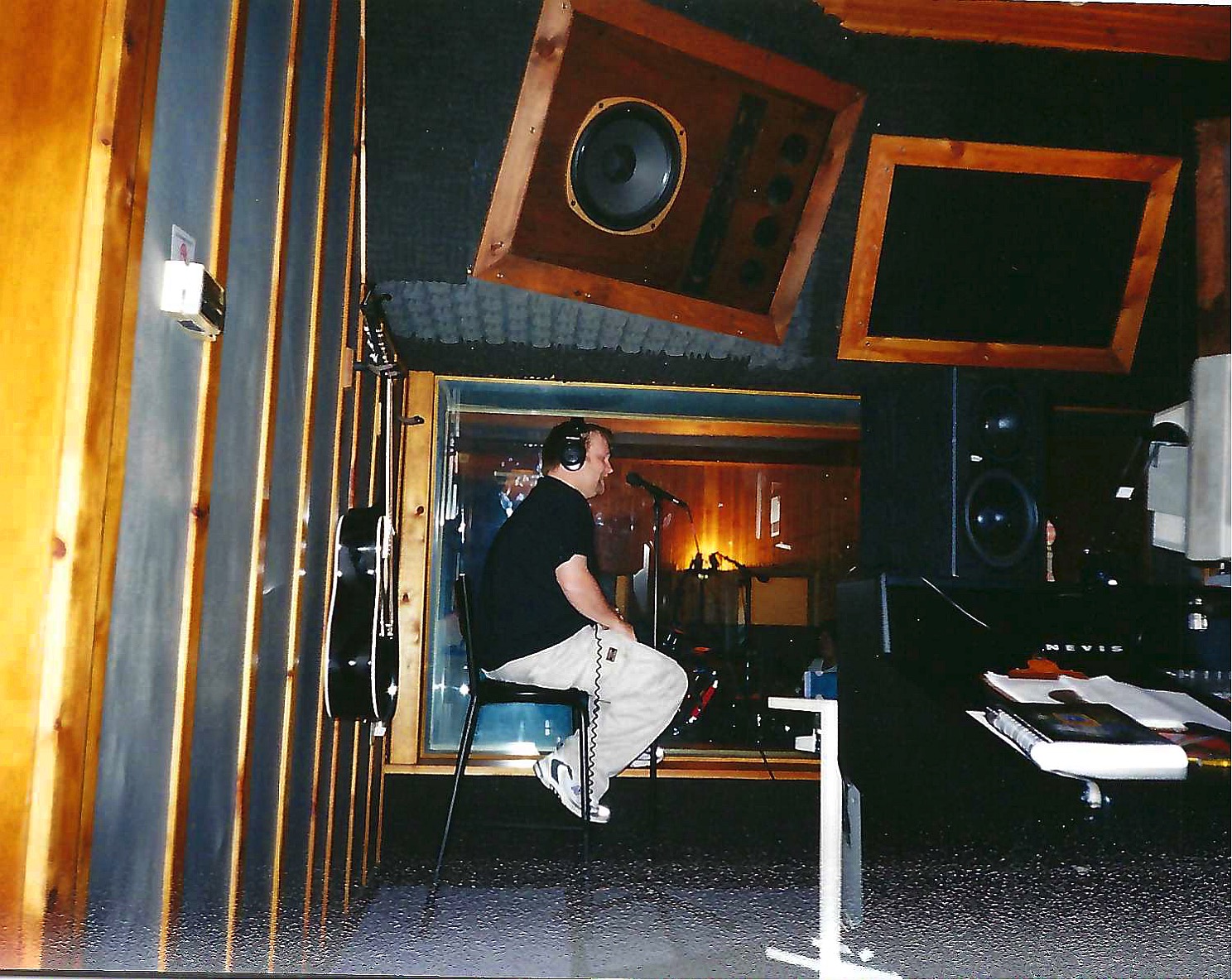 Man recording vocals in the control room at Soundscape Studios, early 2000s, wearing headphones and seated in front of a microphone.