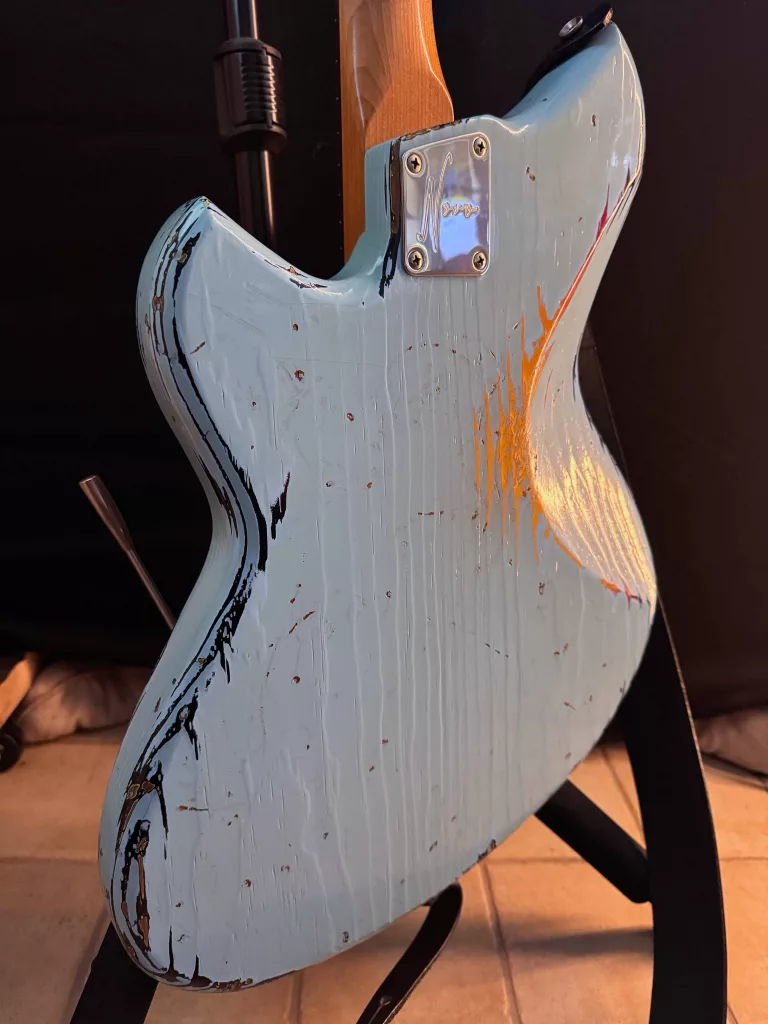 The back of a blue guitar showing wear in the finish