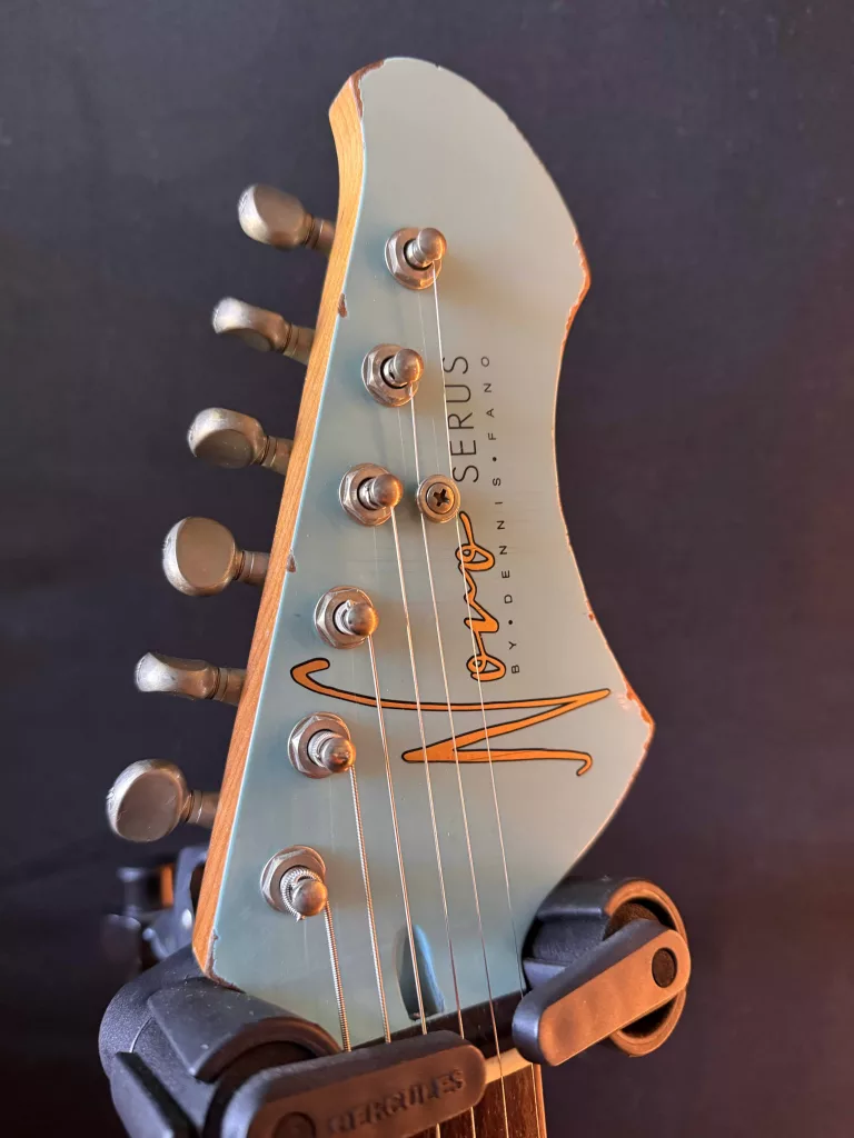 The haedstock of a guitar with a decal sayin Novo guitars by Dennis Fano