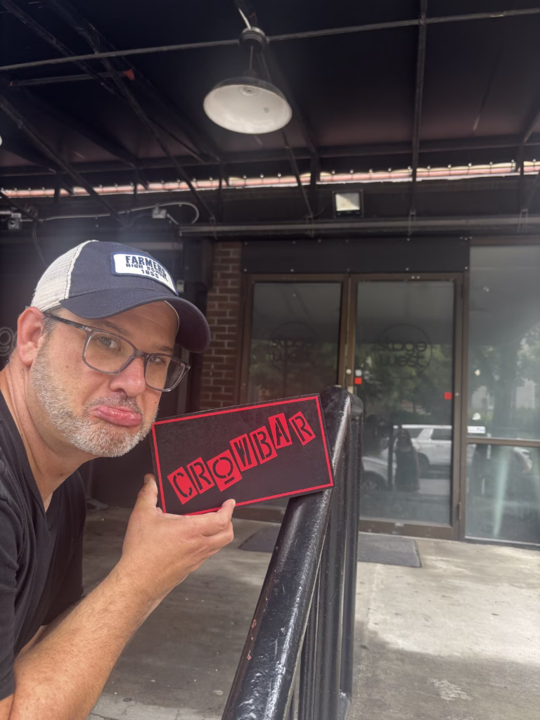 A guy with a sign that says crowbar outside of the old Crowbar in State College PA